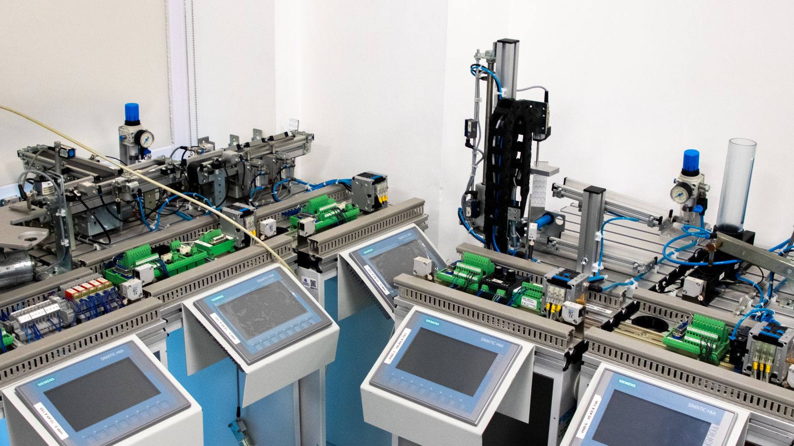Estaciones de automatización industrial con pantallas de control y módulos electrónicos.