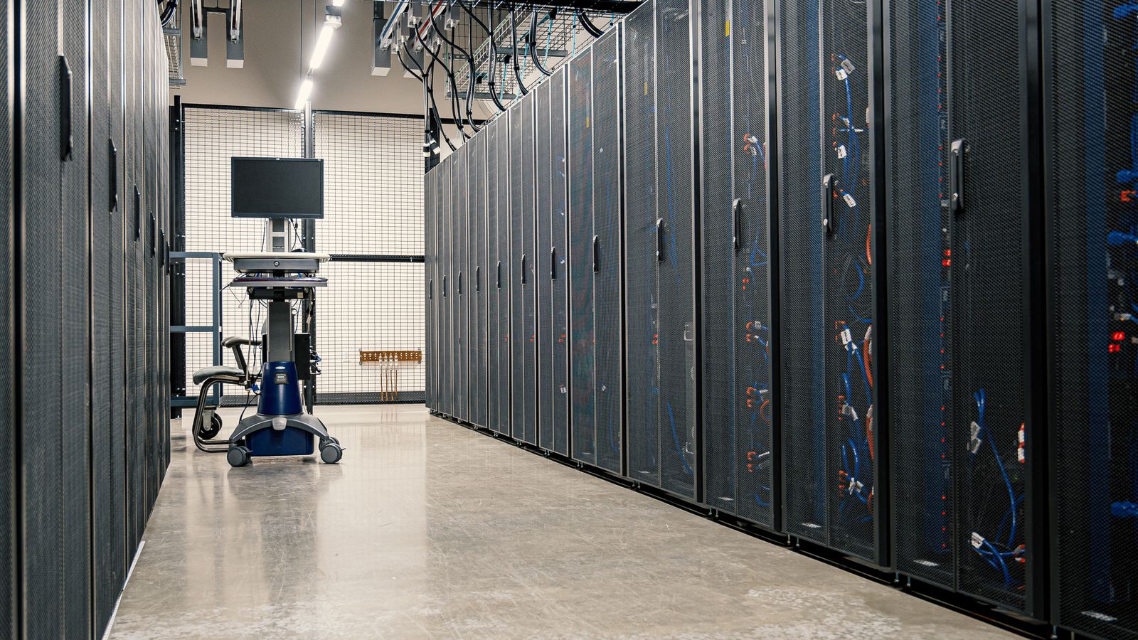 Pasillo entre filas de racks de servidores en un centro de datos.